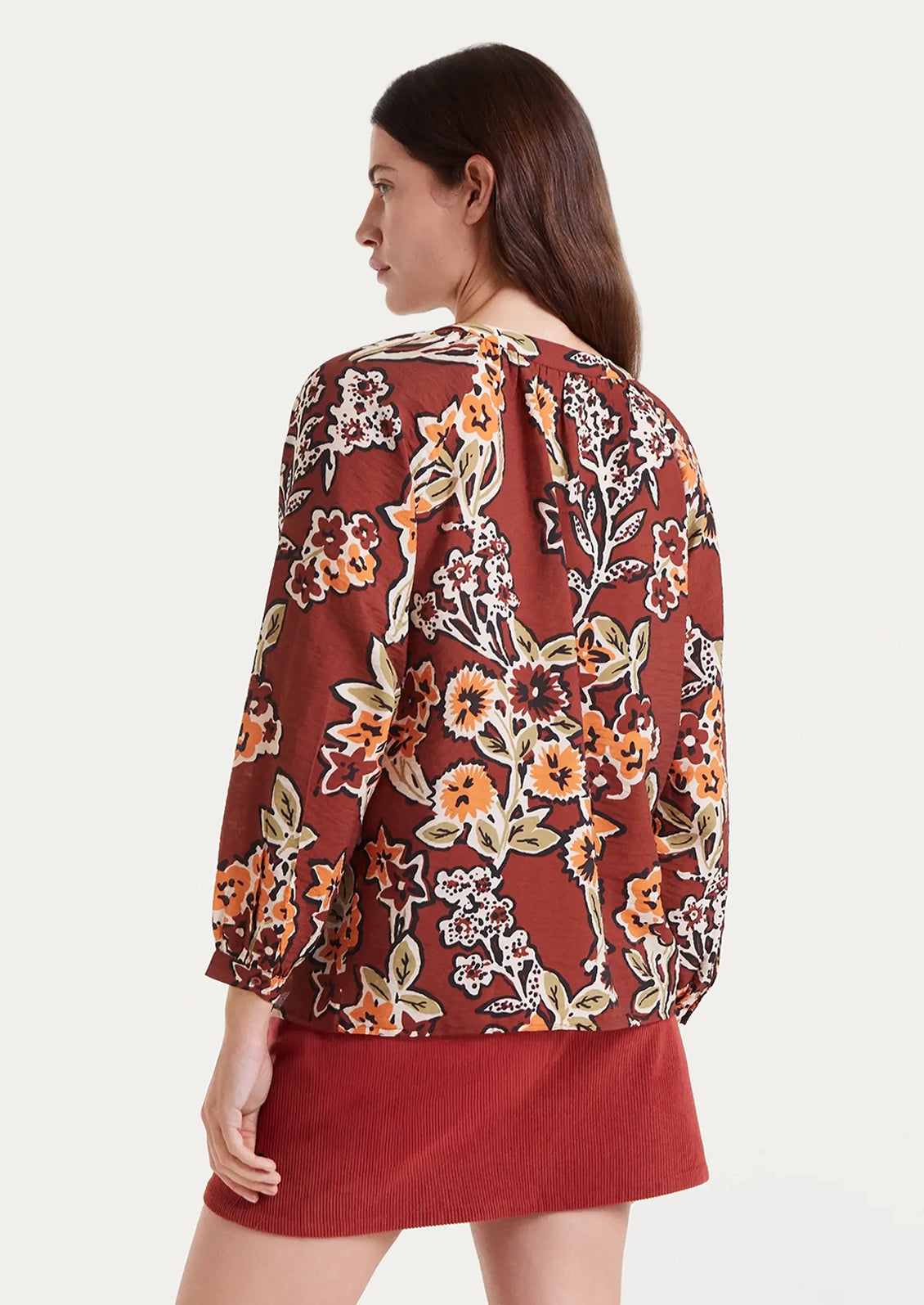 A floral print long sleeve blouse in rust with orange floral pattern.