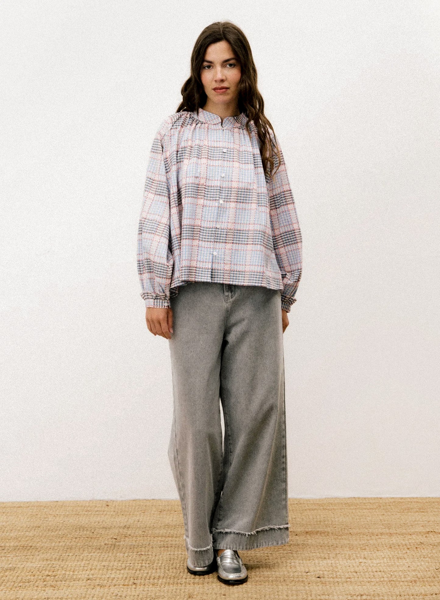 A person wearing a long sleeve blouse with blue and red plaid pattern.