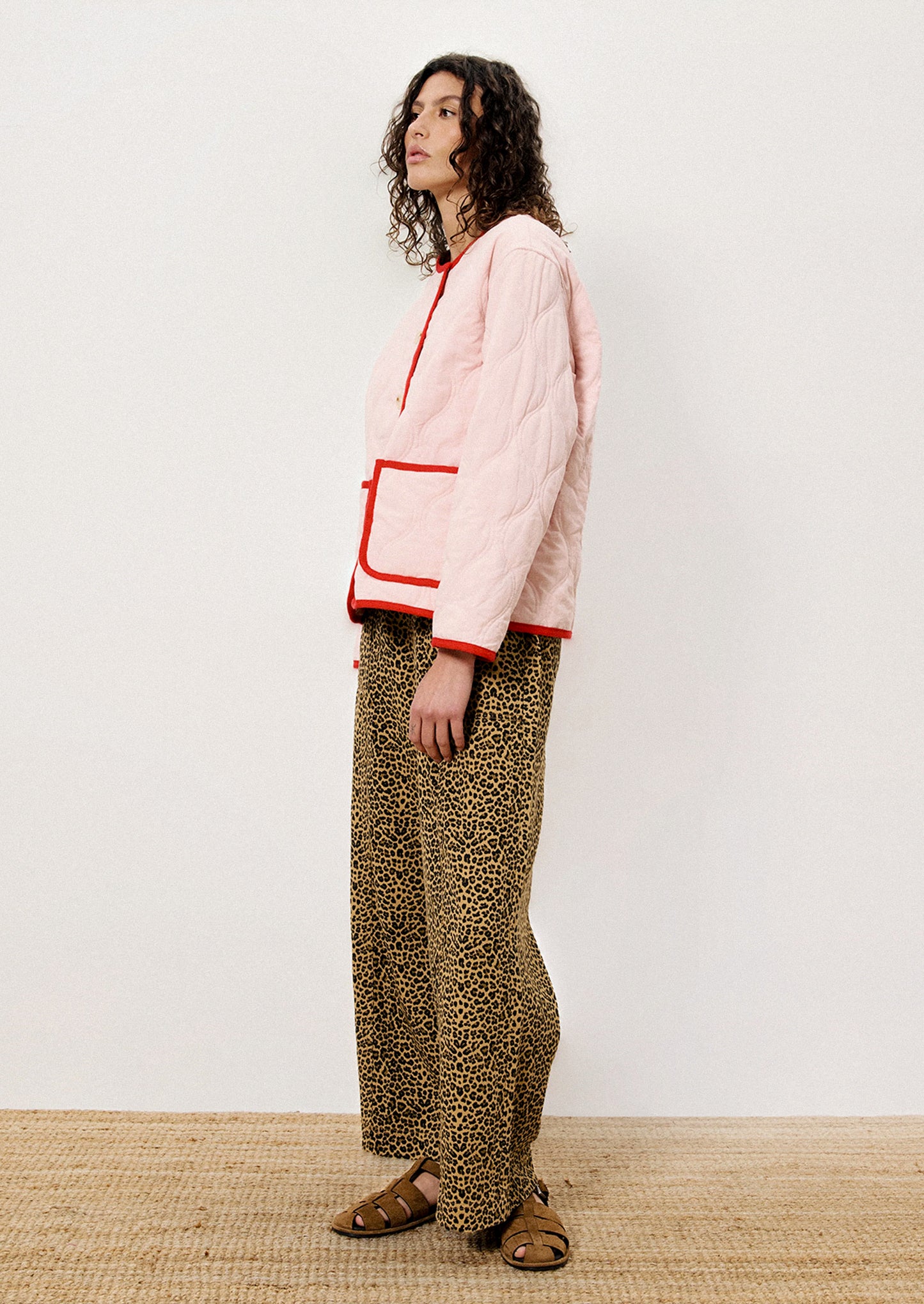 A person wearing a pink quilted jacket with red trim.