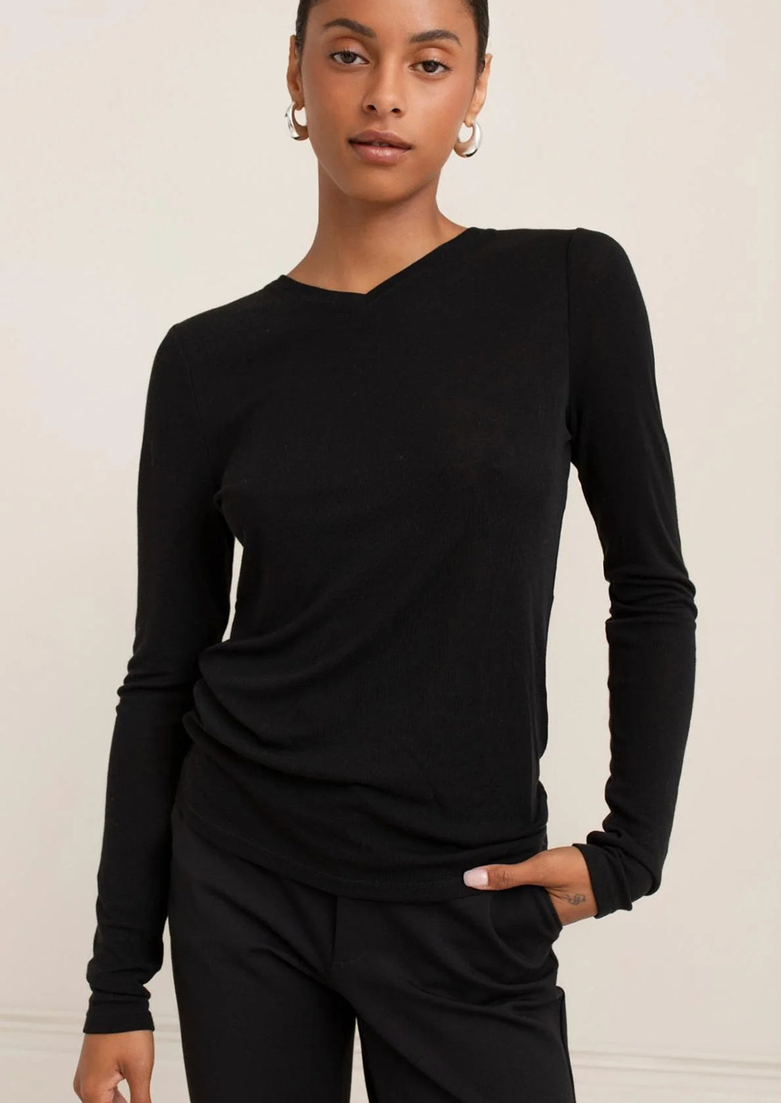 Woman wearing a black long-sleeve top against a plain background