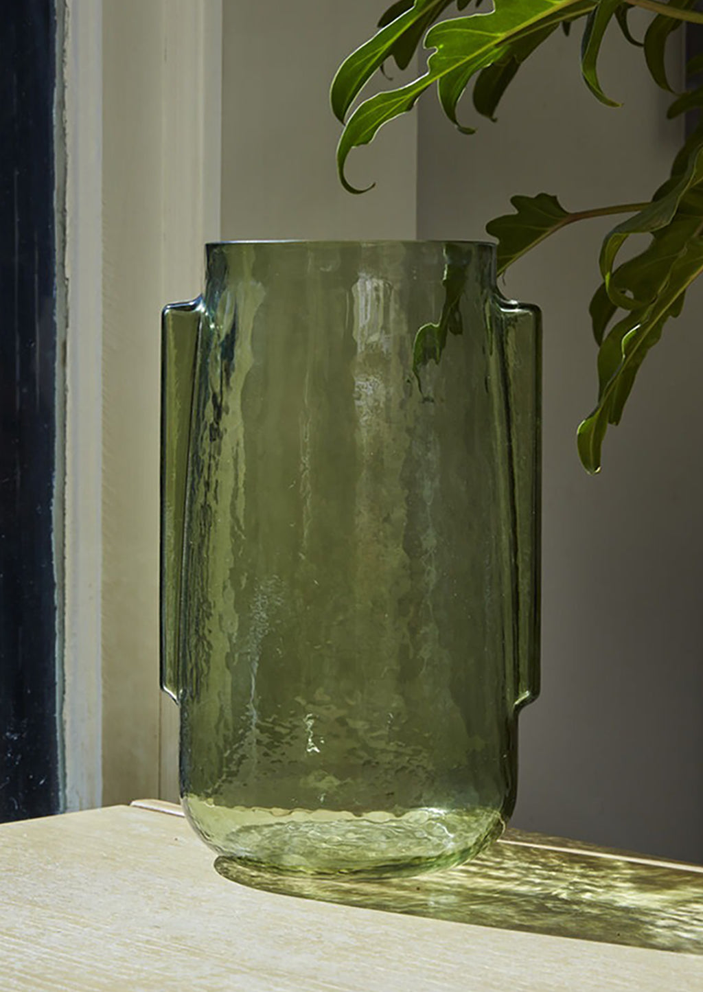 1: A transparent green glass vase in tall shape with side handle detail.