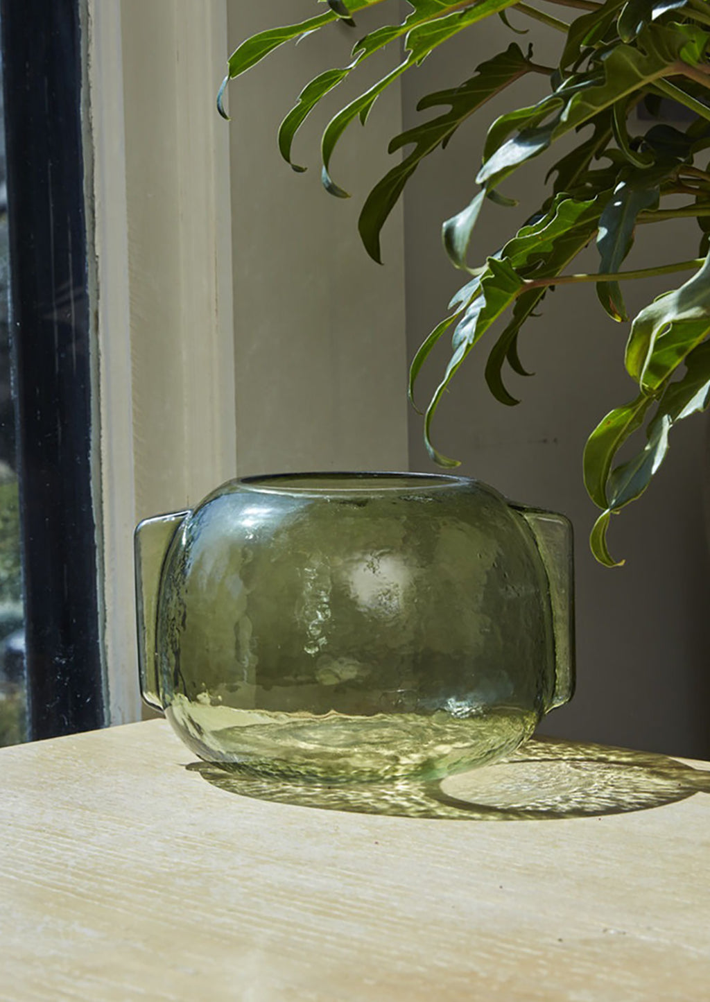 2: A transparent green glass vase in short/wide shape with side handle detail.