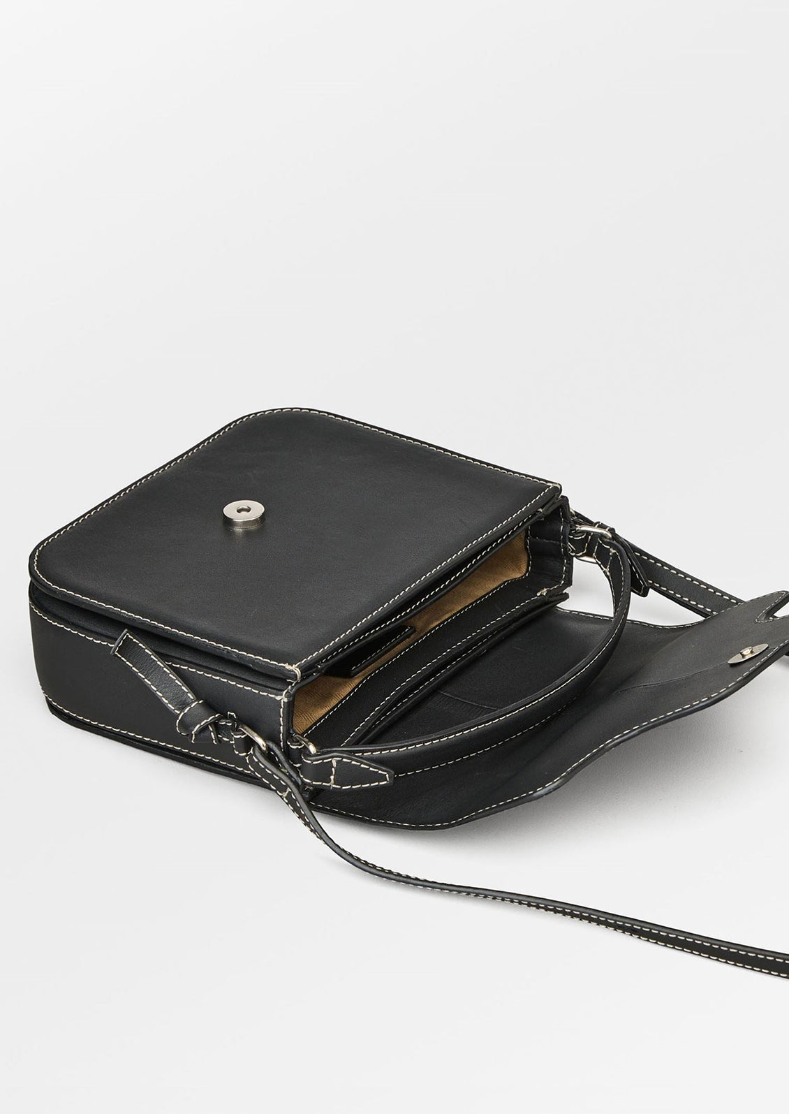 A leather handbag in black with white contrast stitching and flap front design.