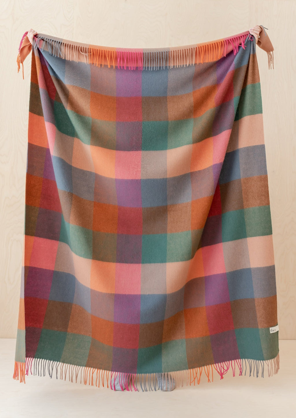 1: A madras check print wool throw in shades of peach, pink, teal, orange and blue.