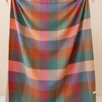 1: A madras check print wool throw in shades of peach, pink, teal, orange and blue.