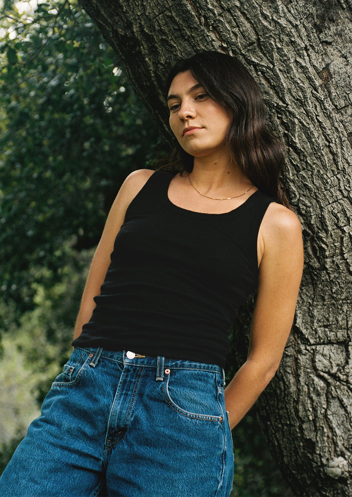 A woman wearing a classic tank top in black with scoop neck.