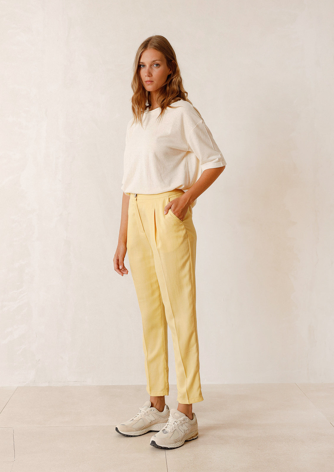 Woman wearing ecru tee, yellow pants, and sneakers.