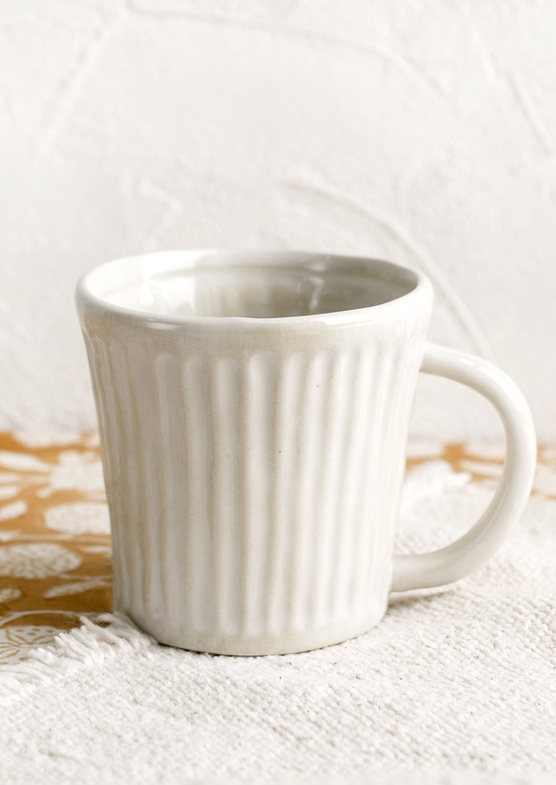A ceramic mug in glossy white glaze with vertical ribbed texture.