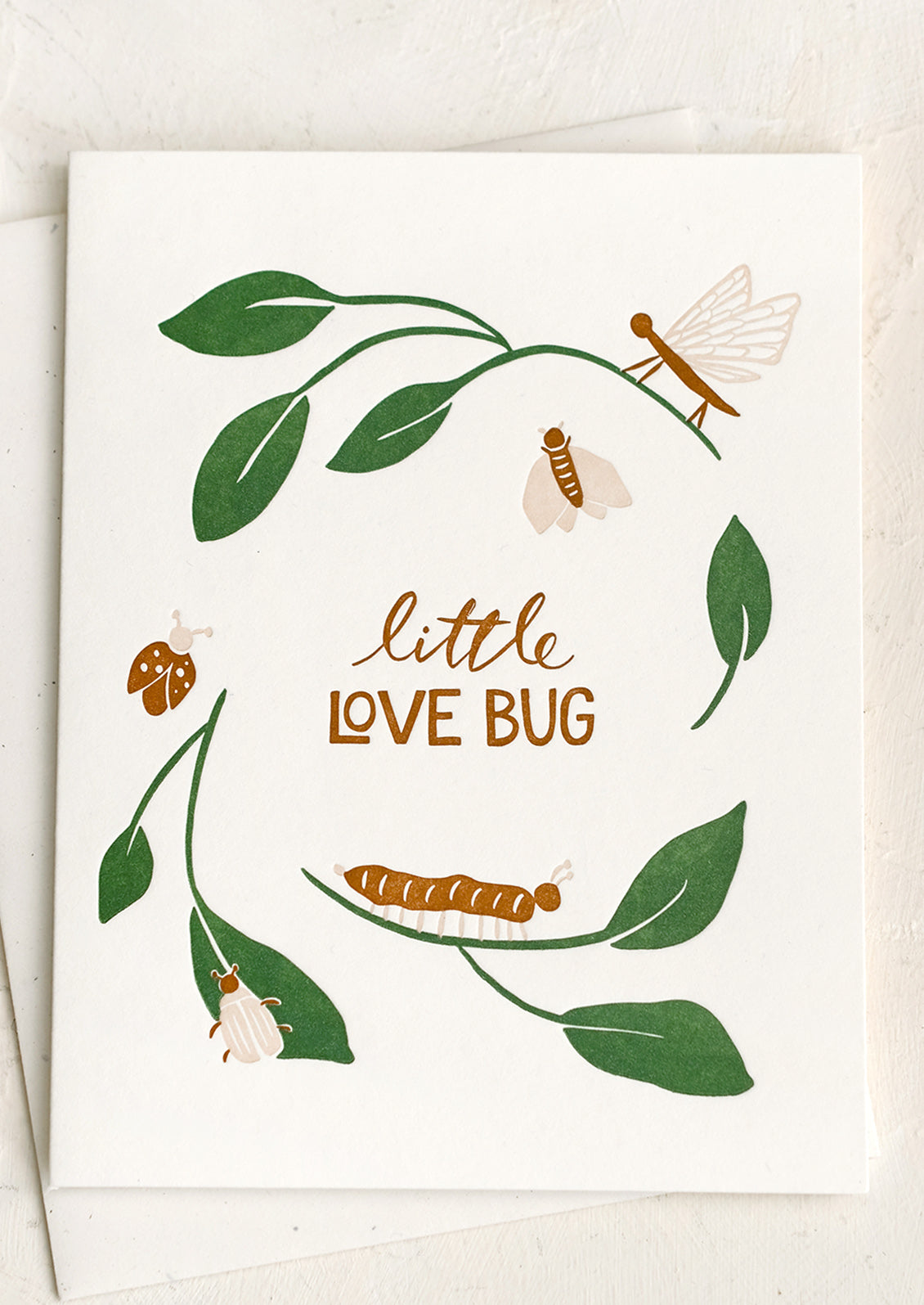 A letterpressed greeting card with bugs on leaves, text reads "Little love bug".