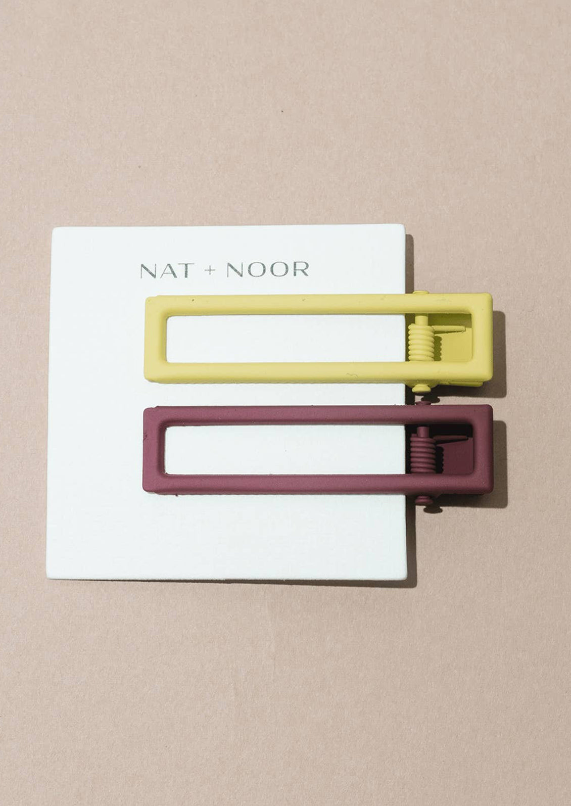 A pair of bar-shaped hair clips in fig and lemon.