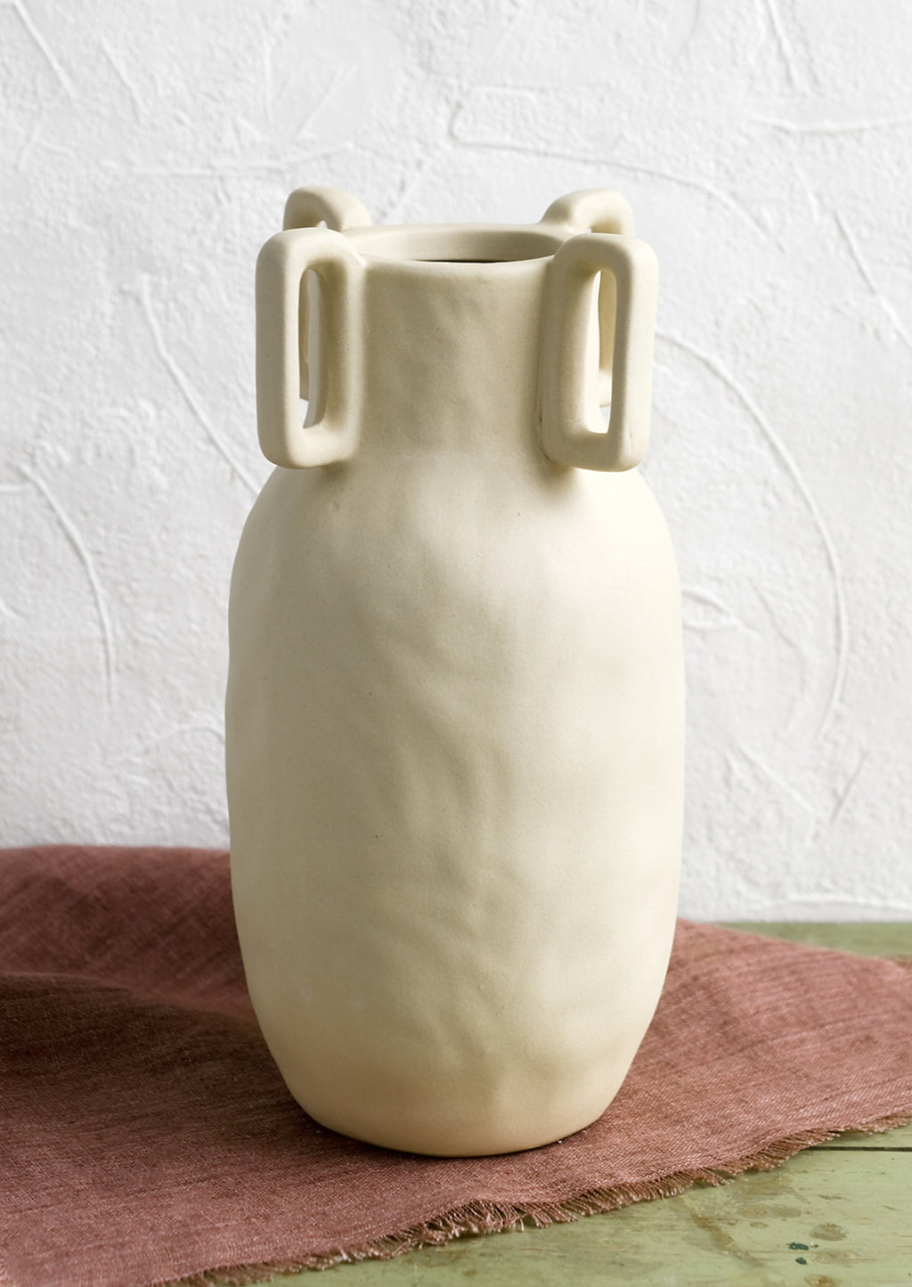 2: A sand color vase in matte ceramic with decorative square handle detail around mouth.