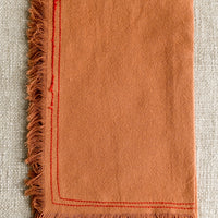 Annatto: An orange tea towel with red stitching.