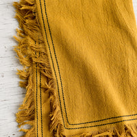 Mustard: A mustard tea towel with navy stitching.