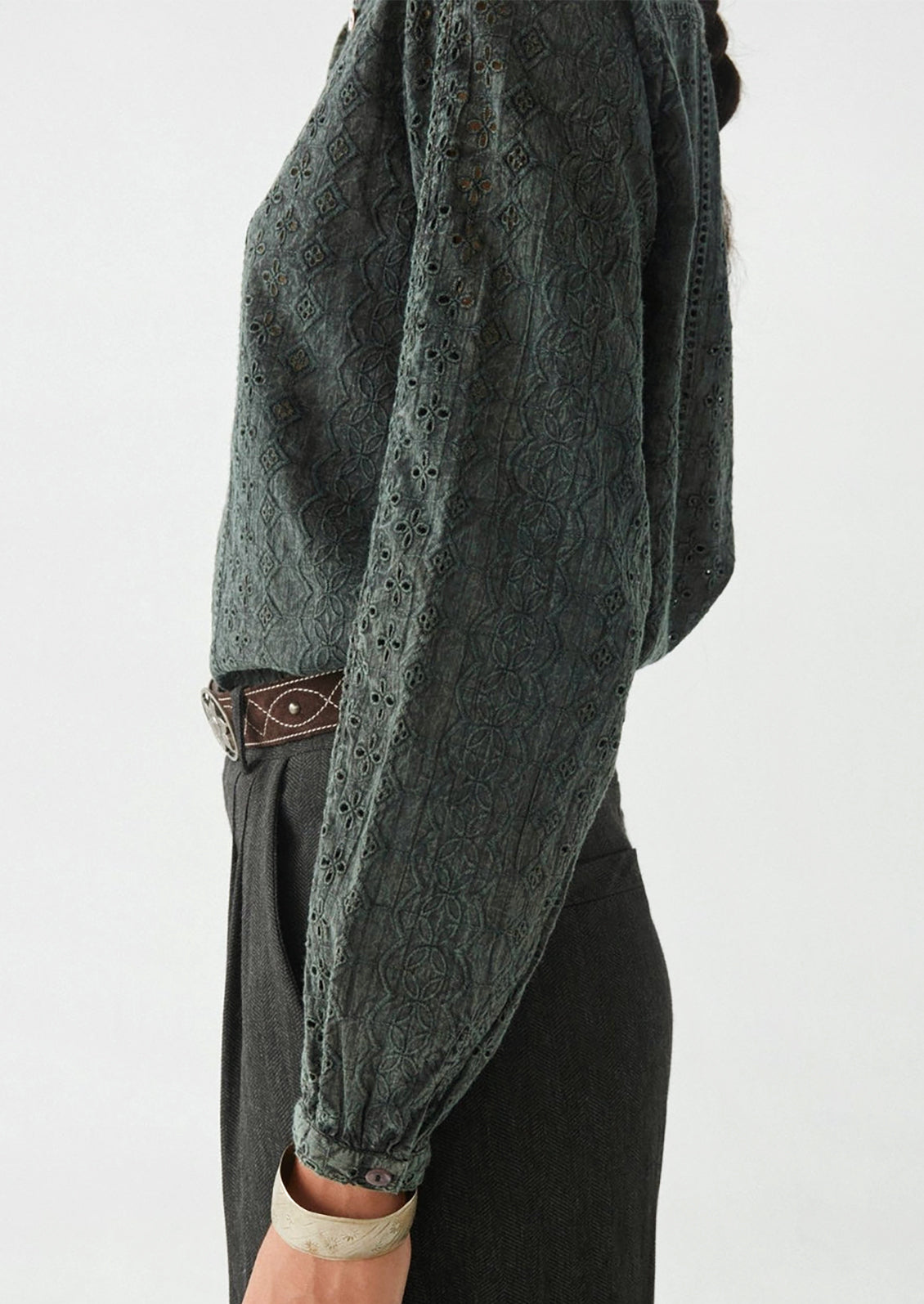 A woman wearing a dark grey cotton eyelet blouse.