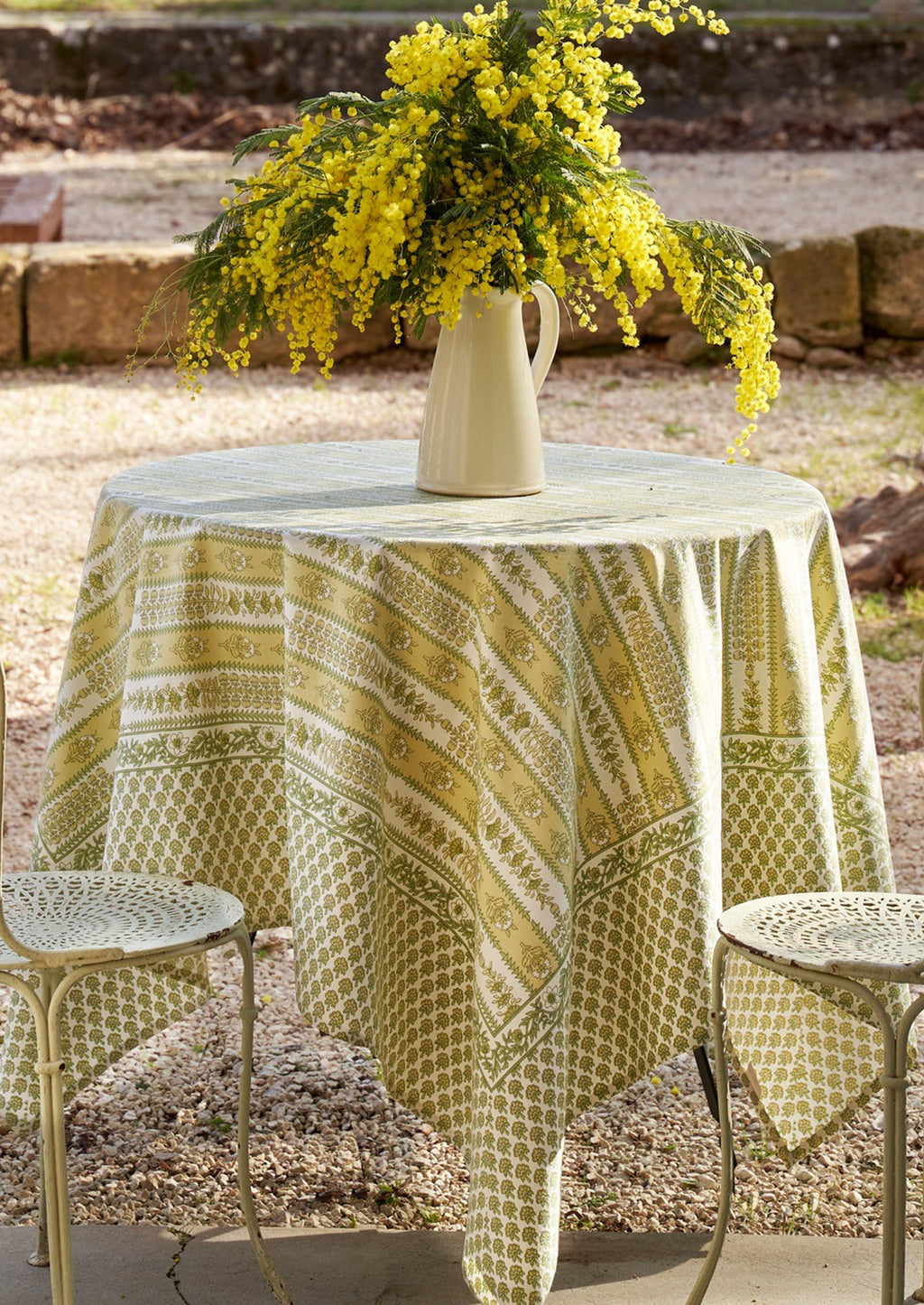 1: A block printed botanical patterned tablecloth in pastel yellow and green tones.