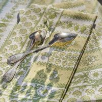 4: A block printed botanical patterned tablecloth in pastel yellow and green tones.