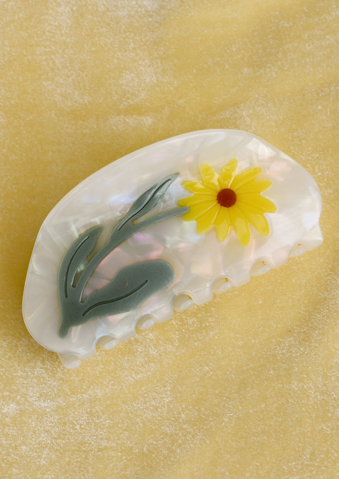 A pearlescent acetate hair claw with yellow daisy.