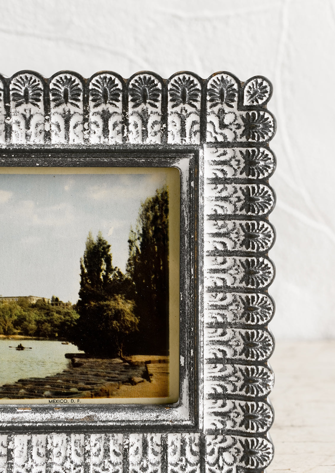 A picture frame with scalloped edges in dark grey with white paint wash.