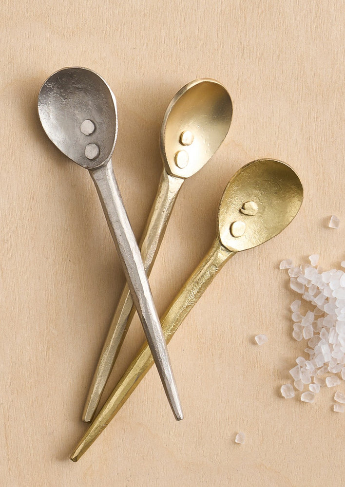 1: Small salt spoons in metal with silver or brass finish.