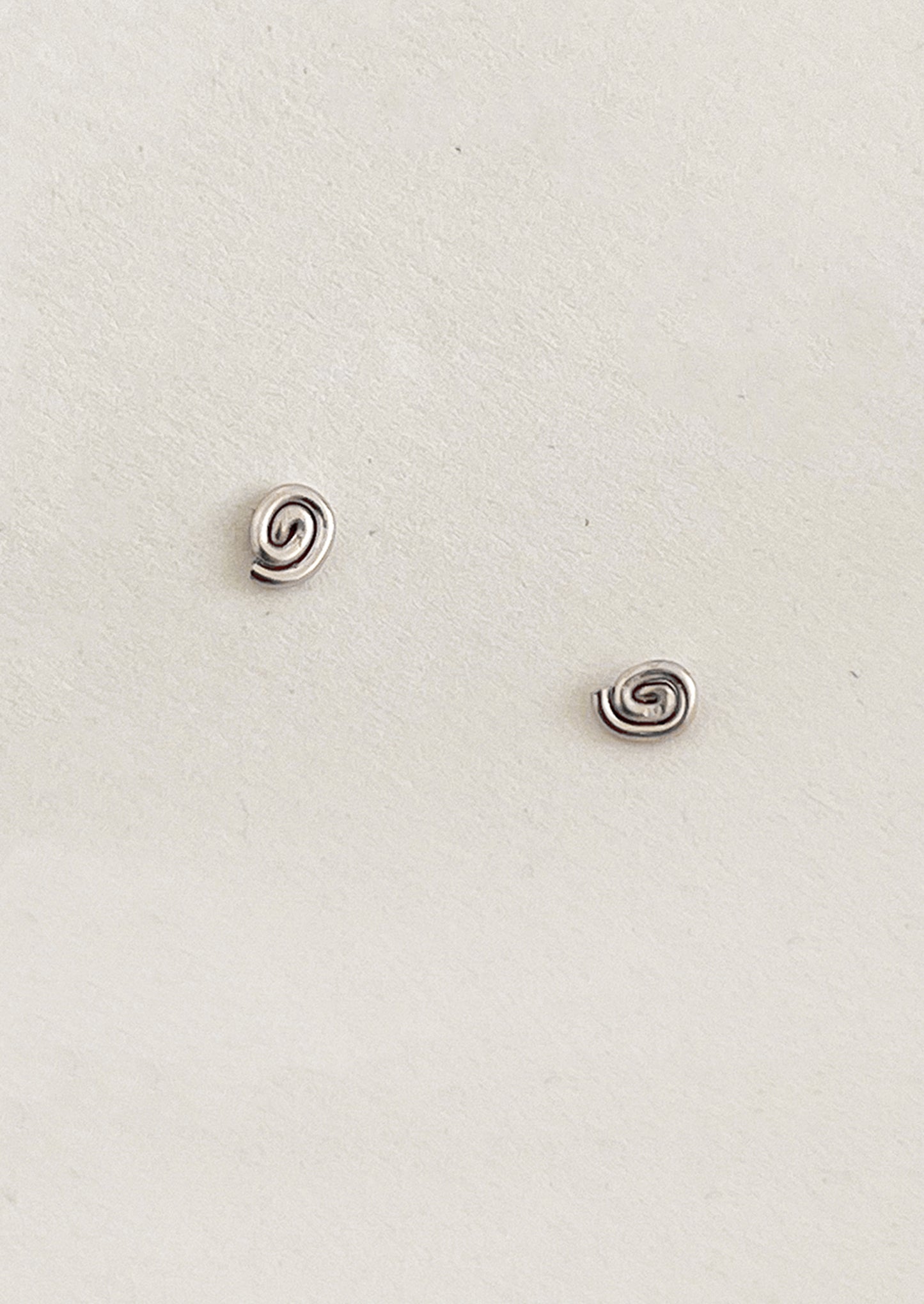 Pair of silver spiral earrings on a light gray background