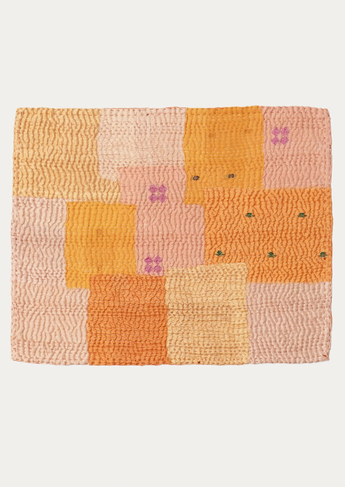 A patchwork placemat made from recycled vintage saris, in pink and orange color palette.