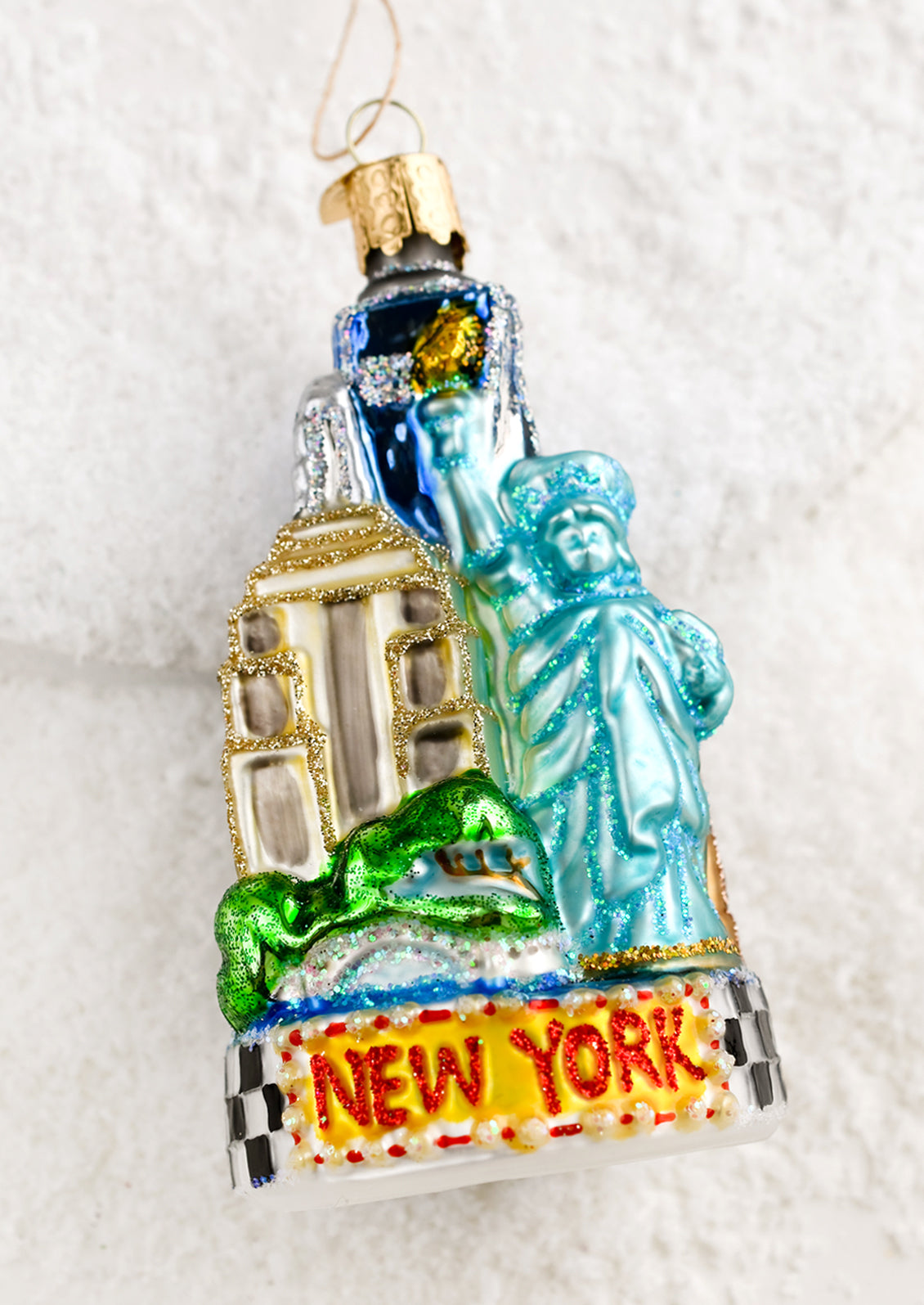 A glass ornament of new york city icons (empire state building, state of liberty).