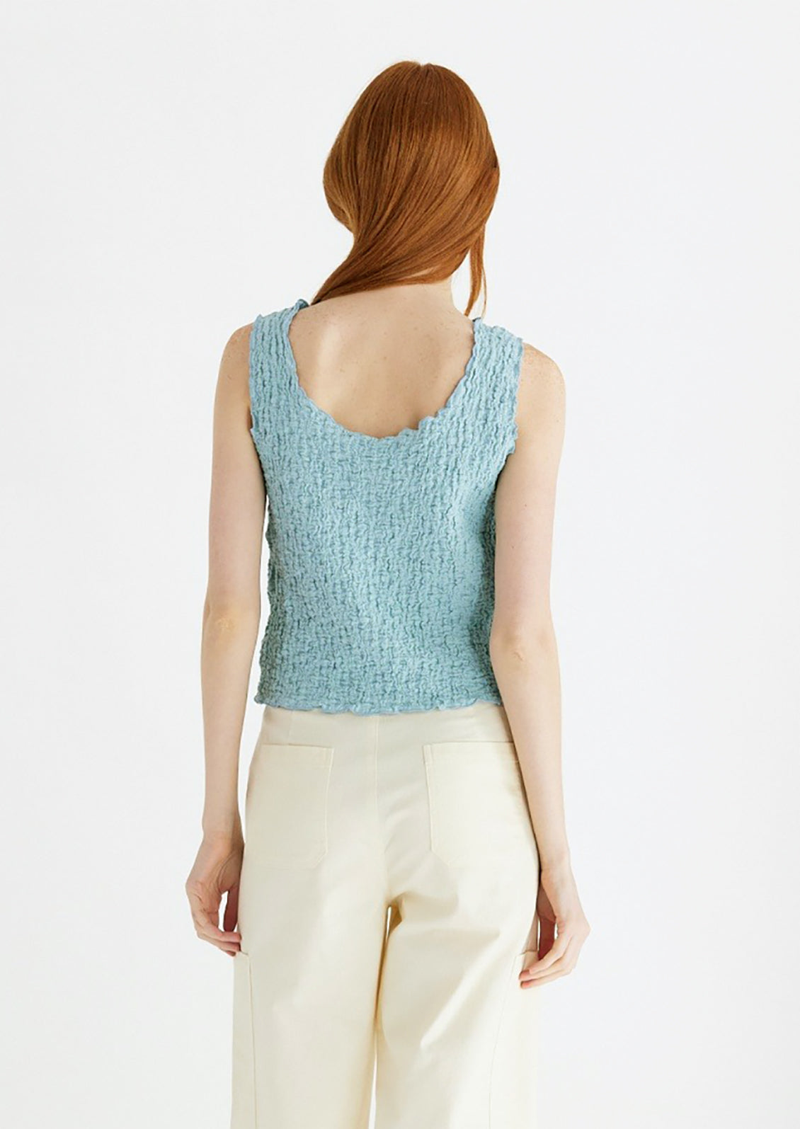 Woman wearing cyan tank top, seen from behind.