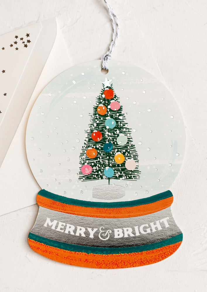 1: A card cut in the shape of a snow globe, text reads "Merry & Bright".