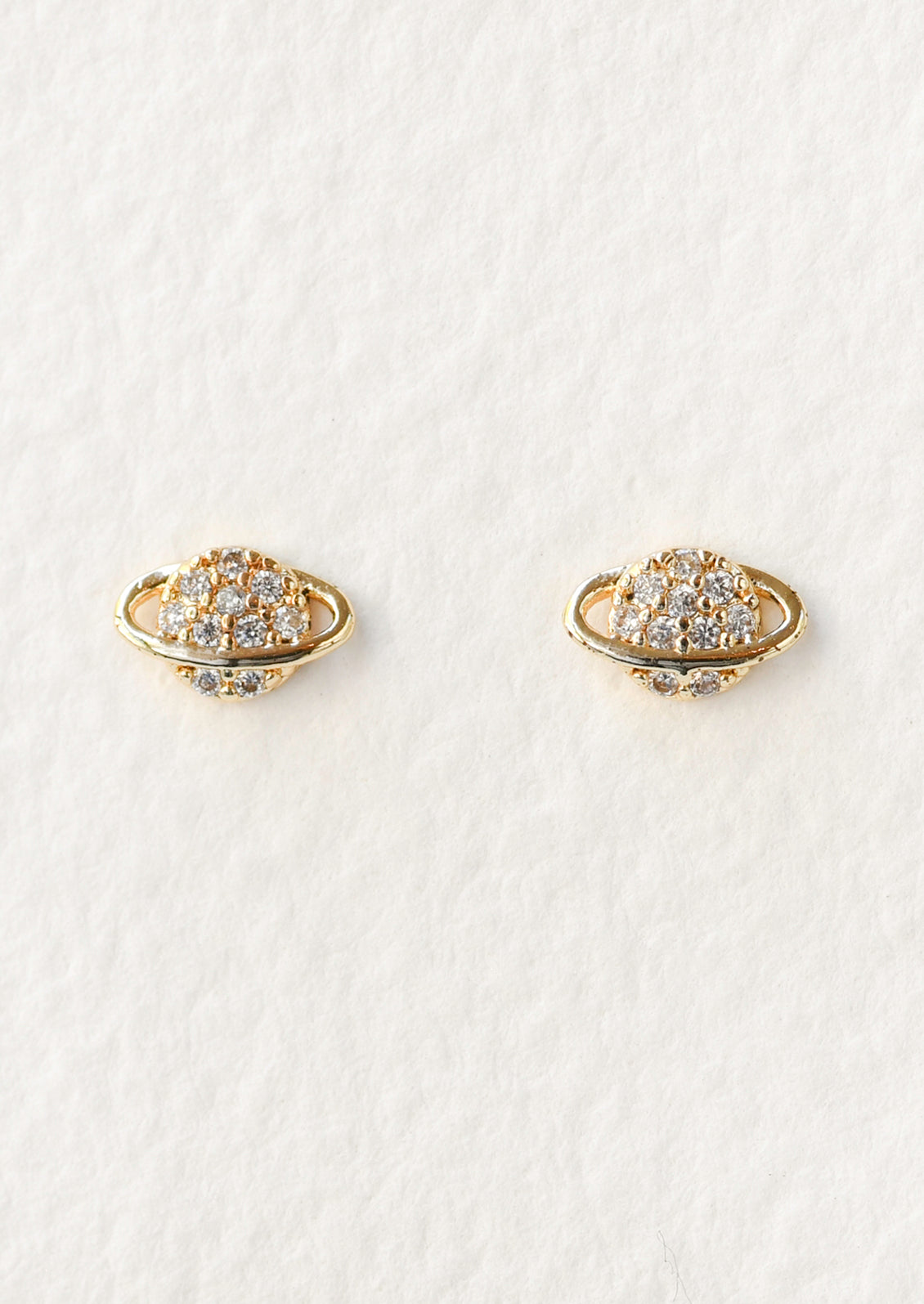 A pair of gold planet shaped stud earrings with cubic zirconia gems in the center.