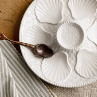 2: A glossy white ceramic plate with shell design.