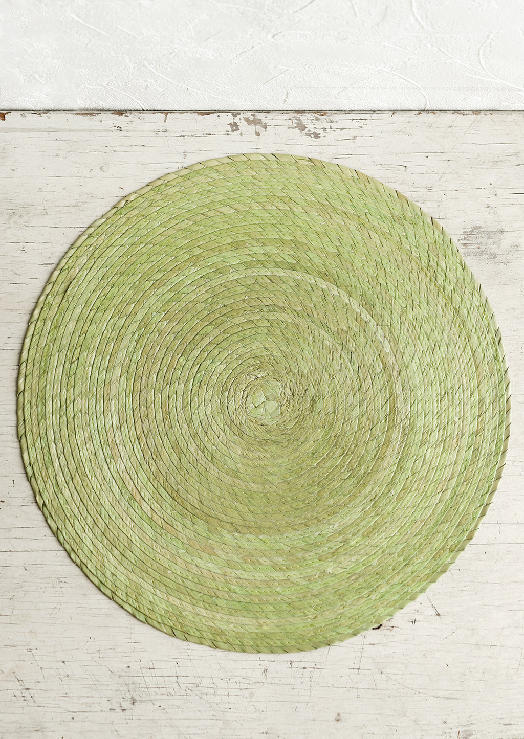 Pistachio: A round woven straw placemat in pistachio color.