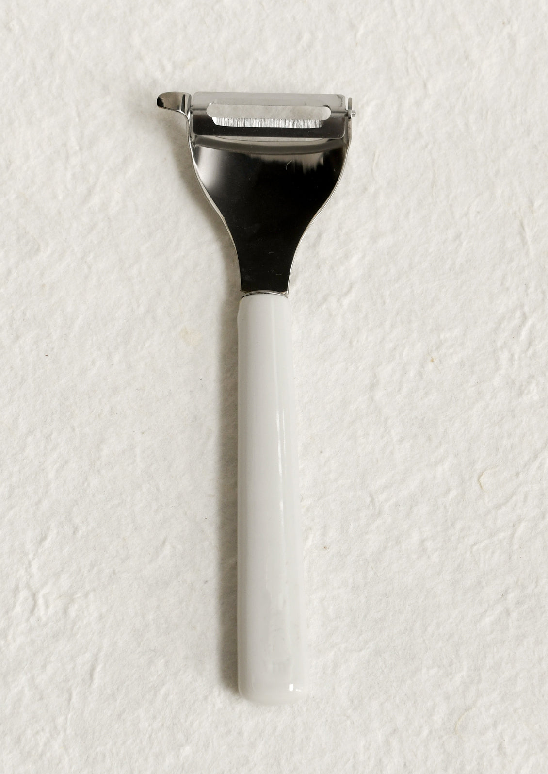 A vegetable peeler with ceramic white and blue handle with blue text.