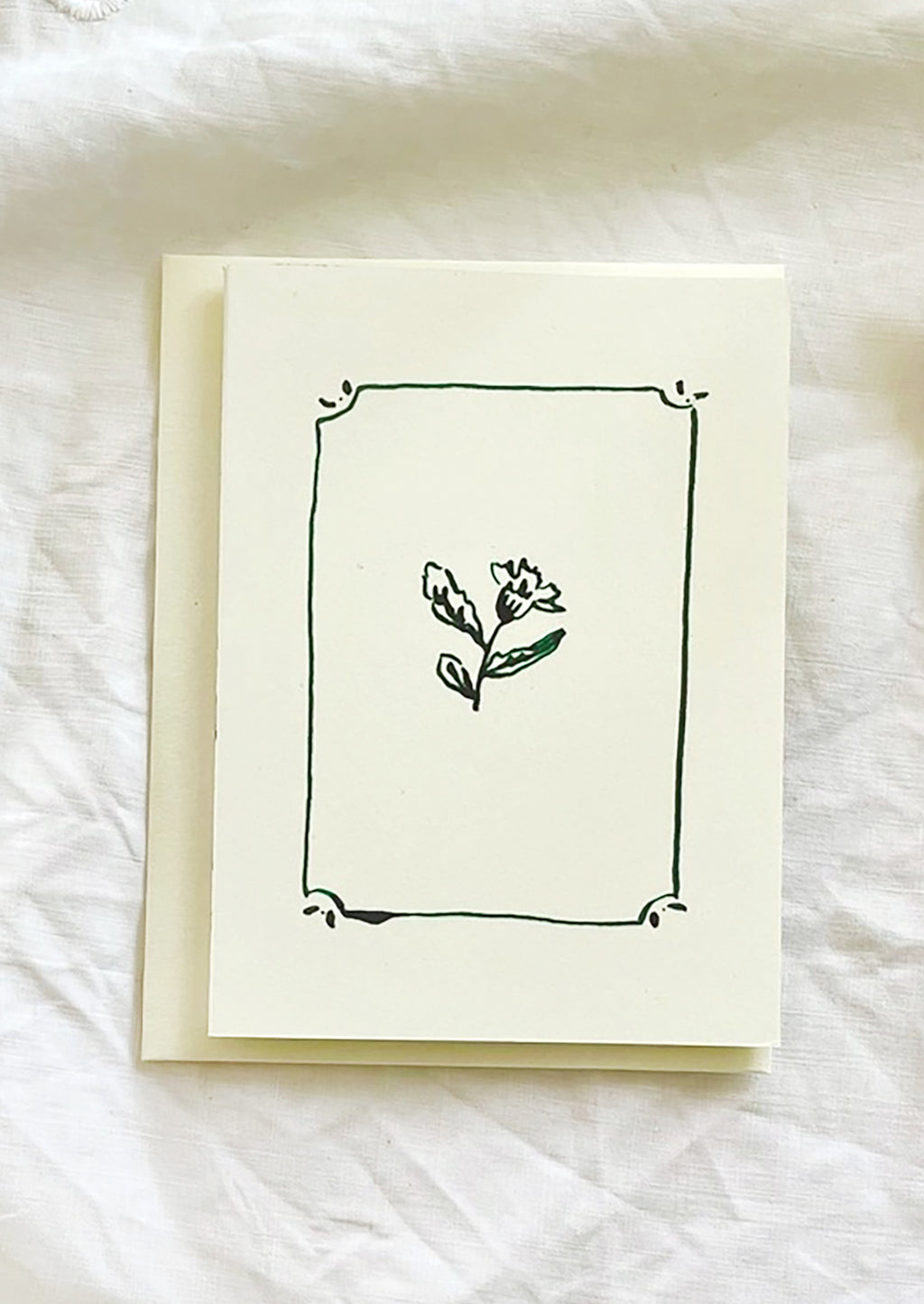 1: A card with framed floral illustration in green ink.