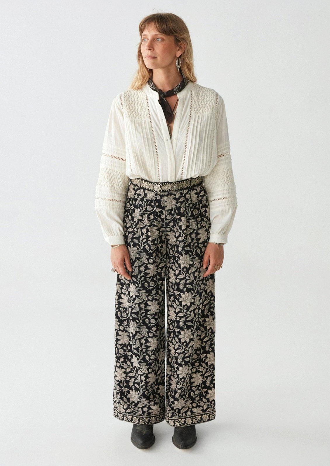 A woman wearing a pair of paisley floral print corduroy pants in black with white flowers.