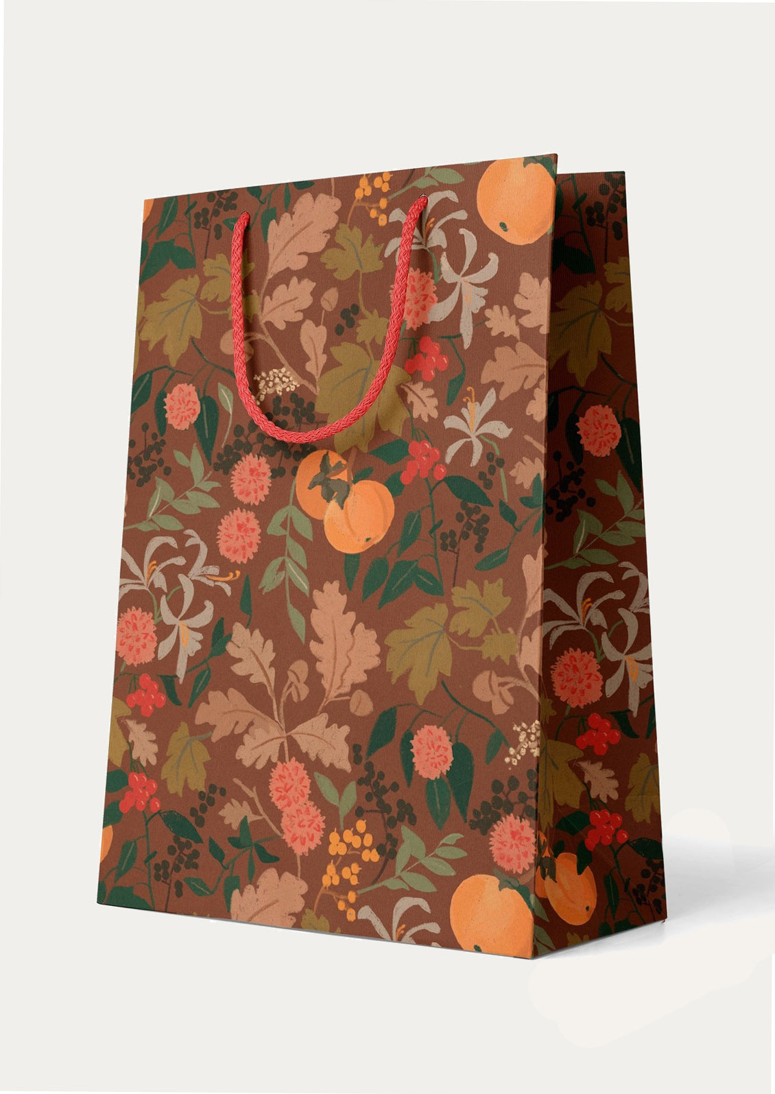 A fruit and floral patterned gift bag with dark brown background and red handle.