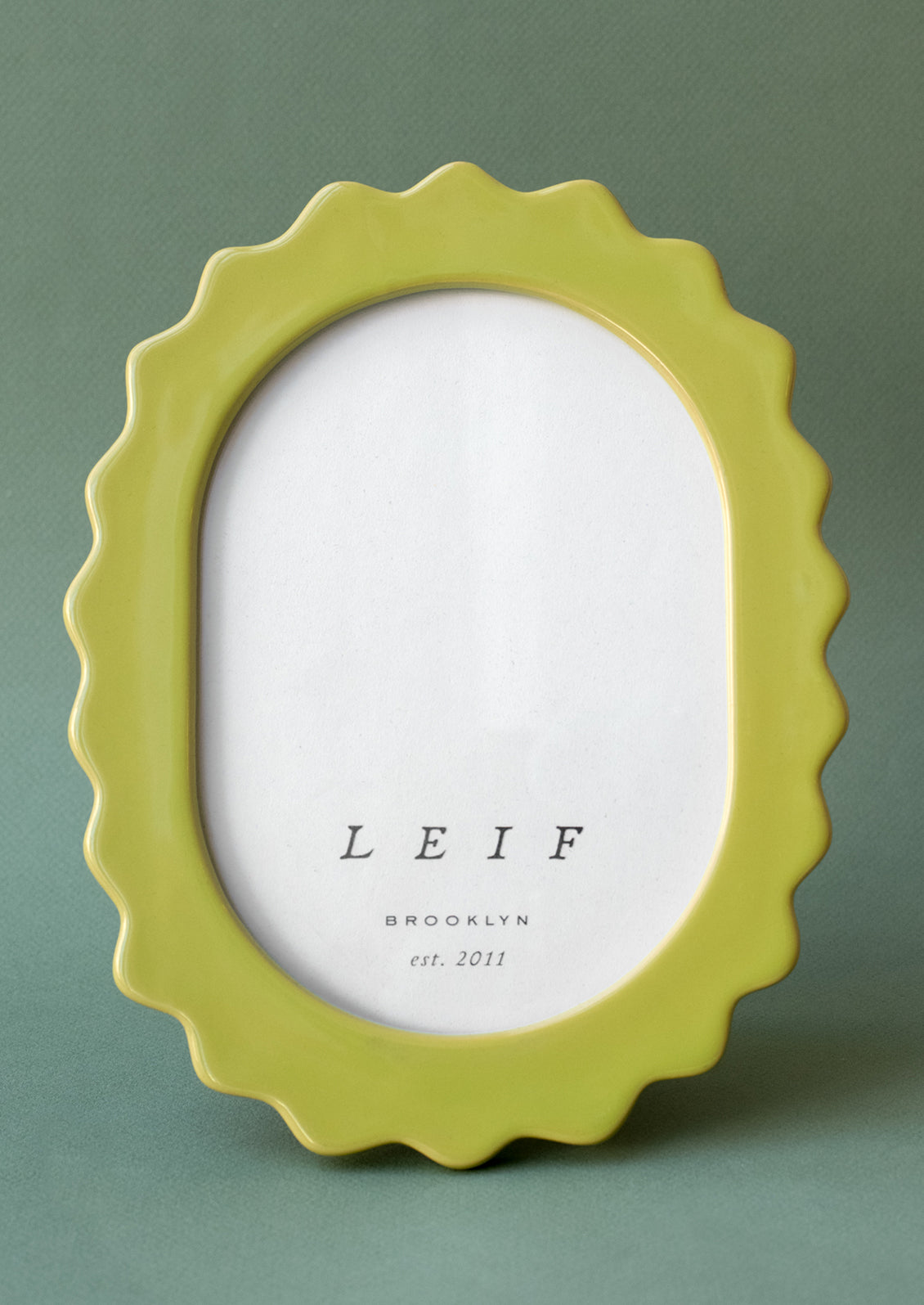 An oval shaped picture frame in wavy squiggle shape in green ceramic.