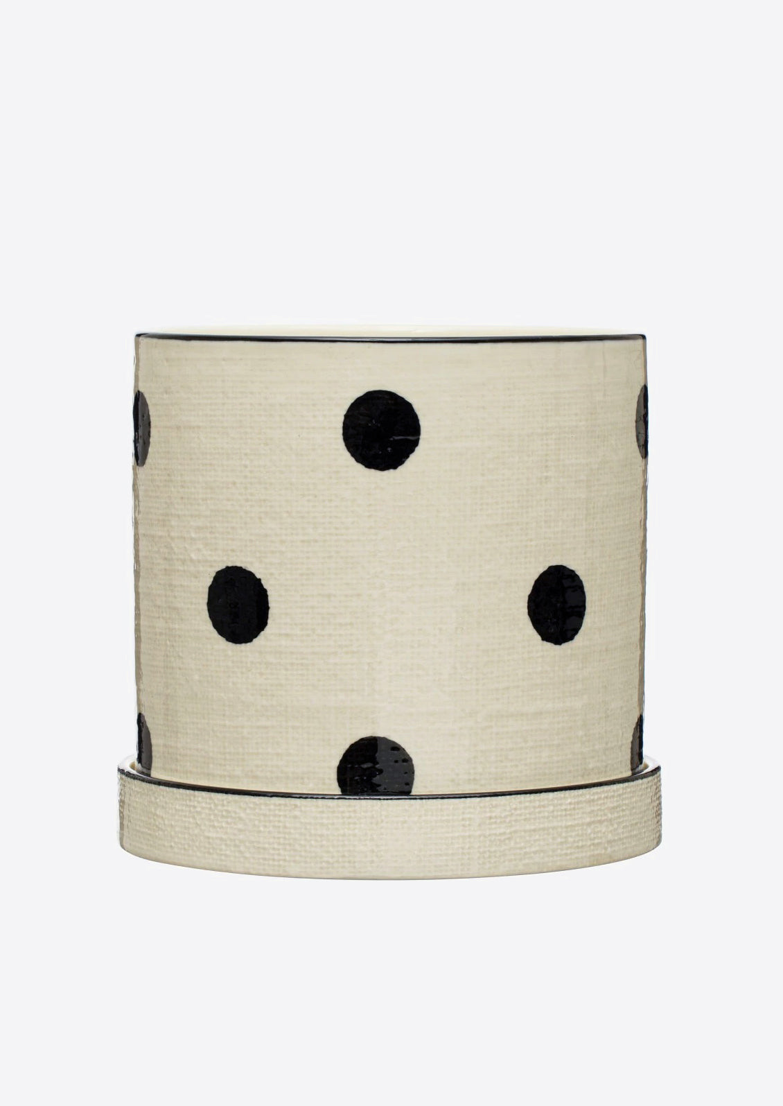 A polka dot ceramic planter in white with black dots, linen texture.