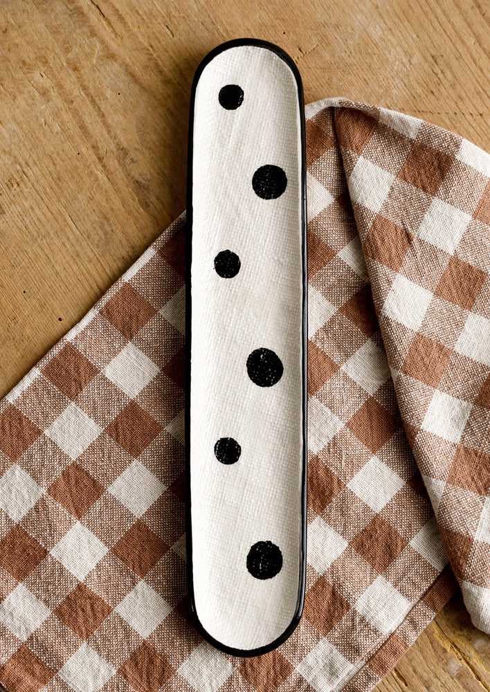 1: An oblong, skinny ceramic platter in cream with black polka dot print.