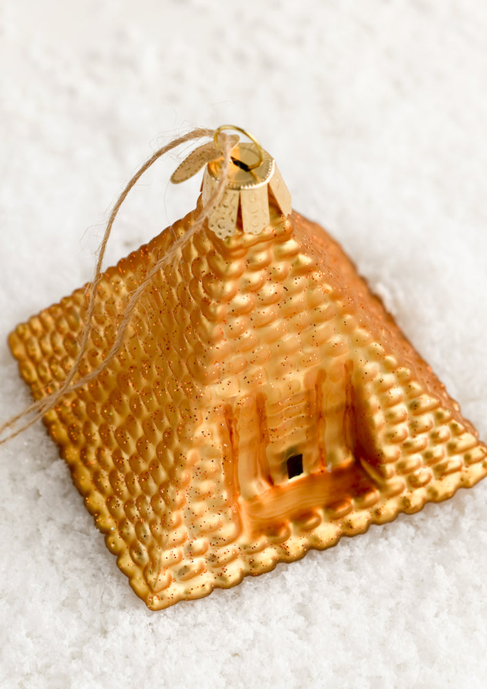 1: A glass holiday ornament in the shape of a golden pyramid.