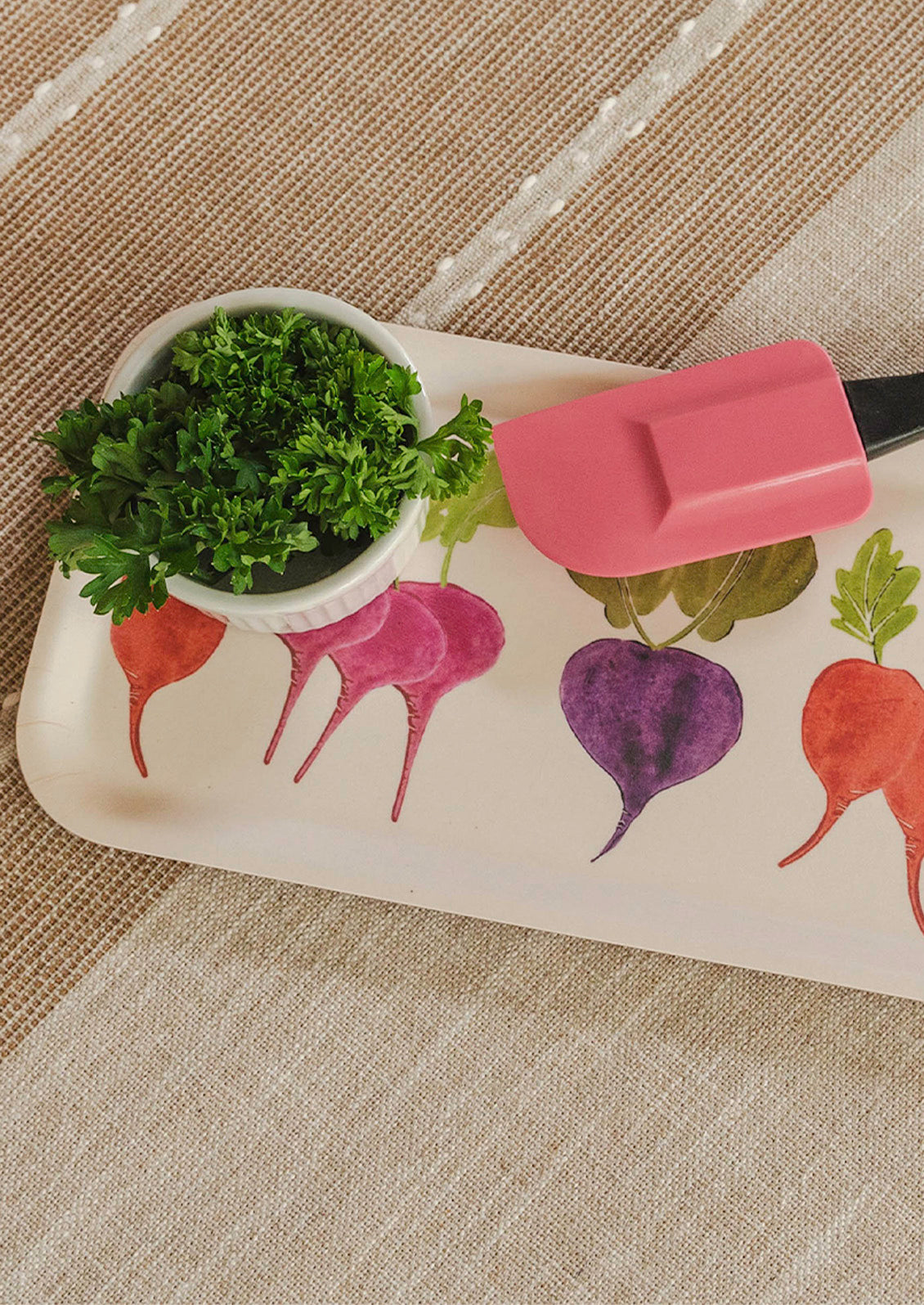 A rectangular wooden tray with an illustration of colorful root vegetables on a table.