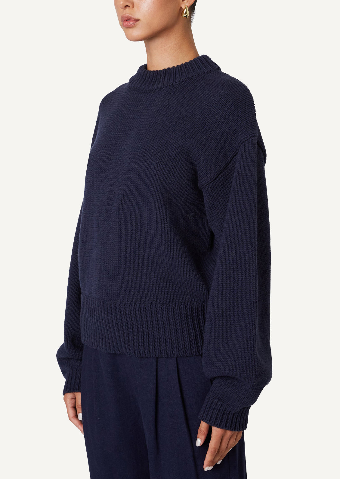 A woman wearing a crewneck sweater in navy.