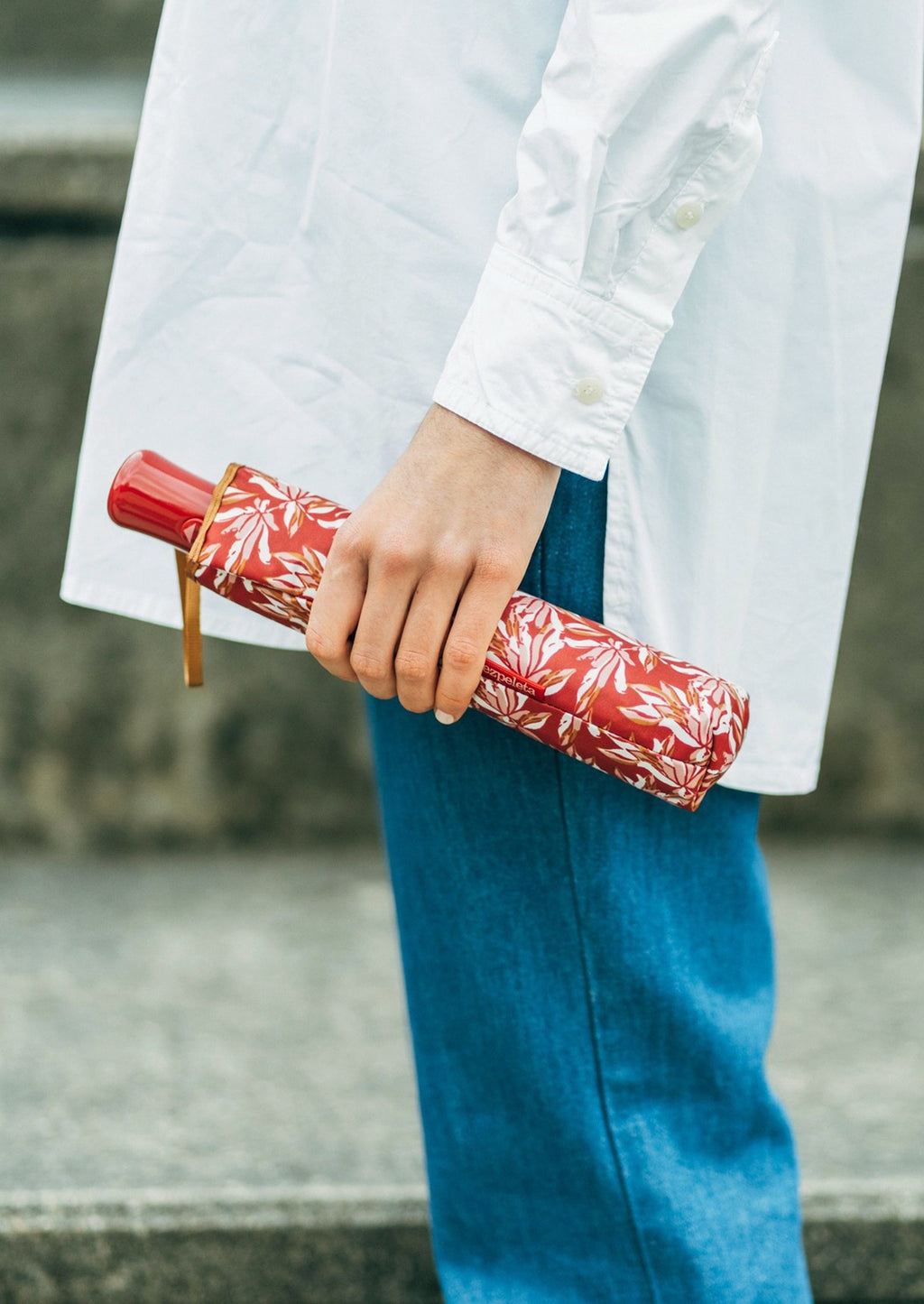 Red / Peach: A woman holding a red floral print umbrella.