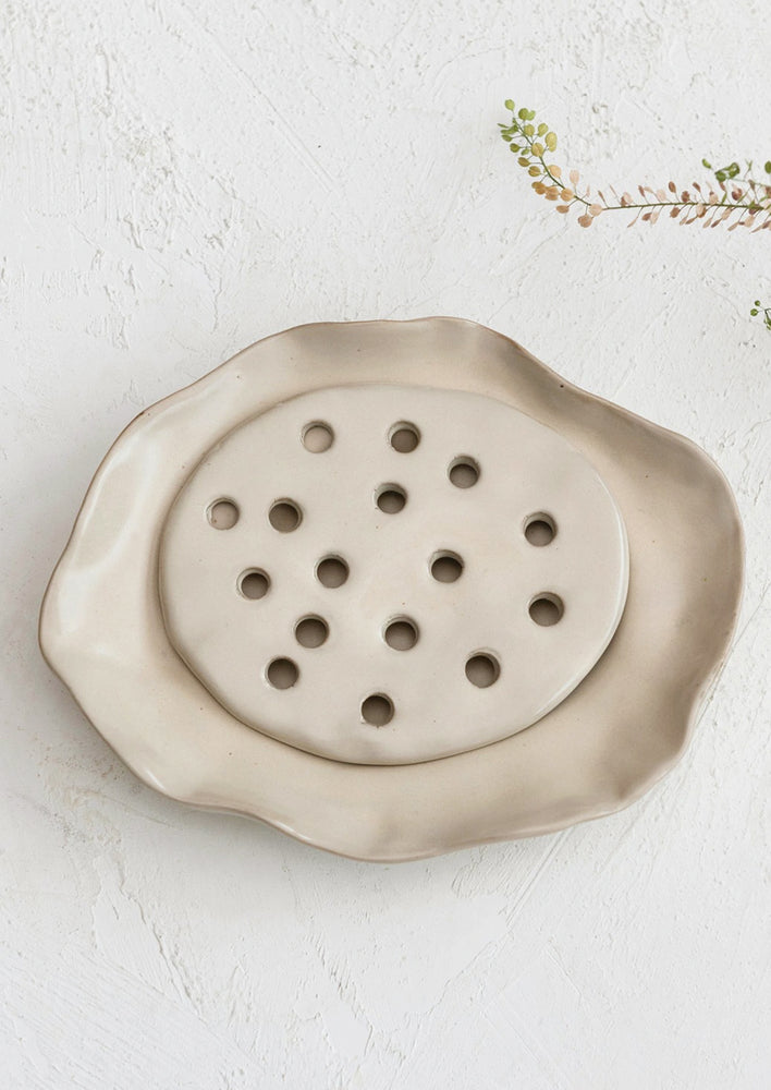 1: A sandy beige ceramic ruffled serving tray with drainage tray.