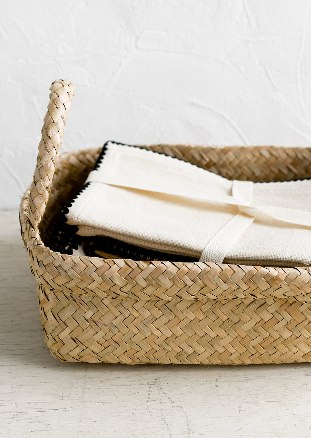 3: A rectangular seagrass basket with rolled top rim and side handles.
