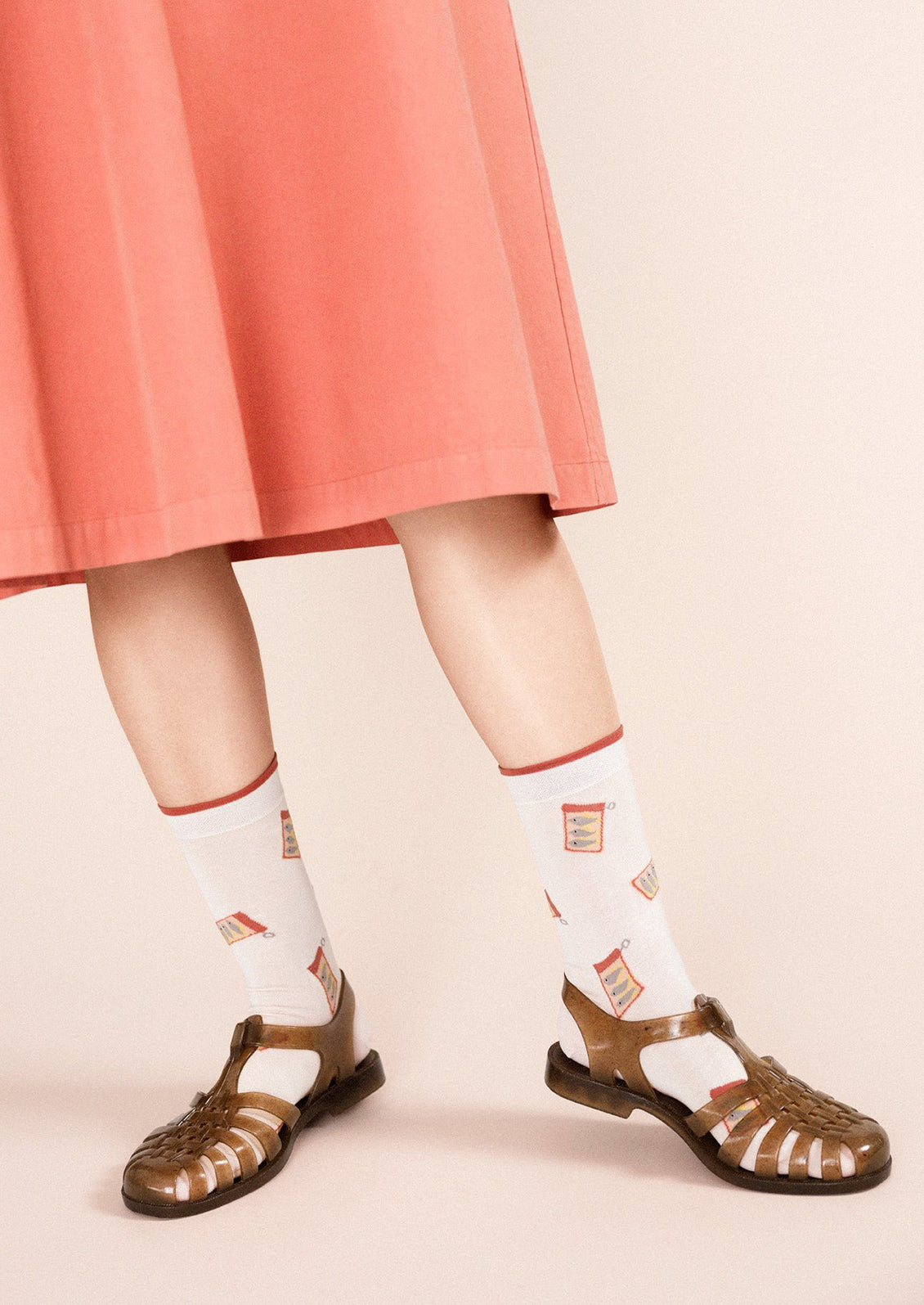 A pair of blush colored socks with tinned sardine pattern.
