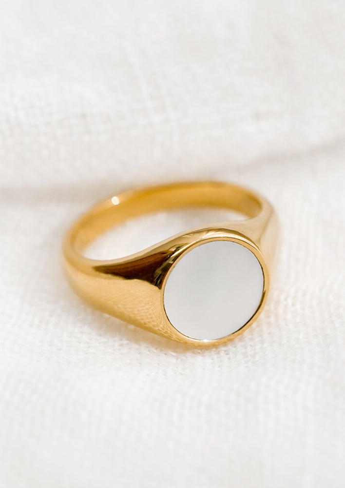 A chunky gold signet ring with white shell.