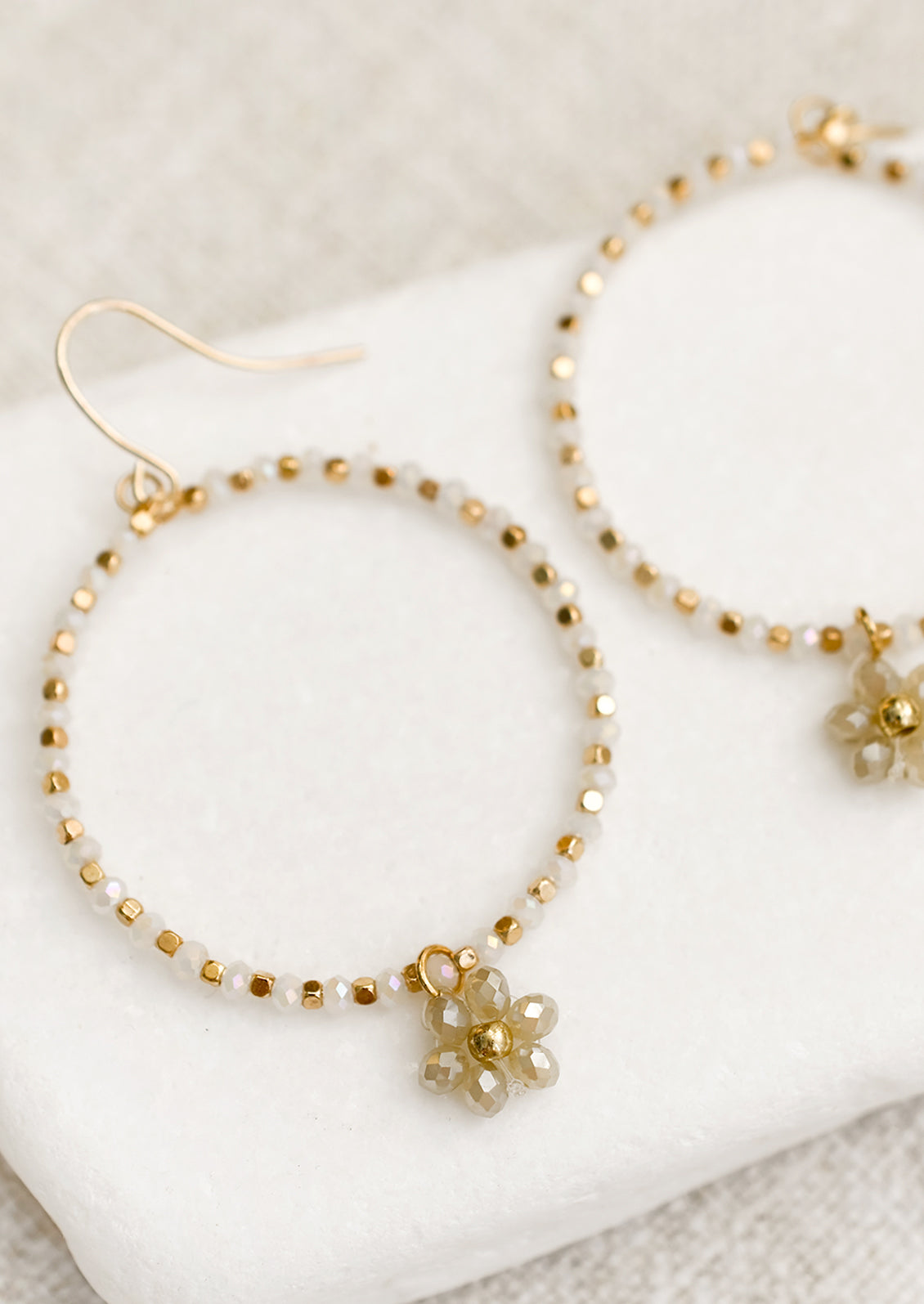 A pair of beaded hoop earrings with flower charm in moonstone..
