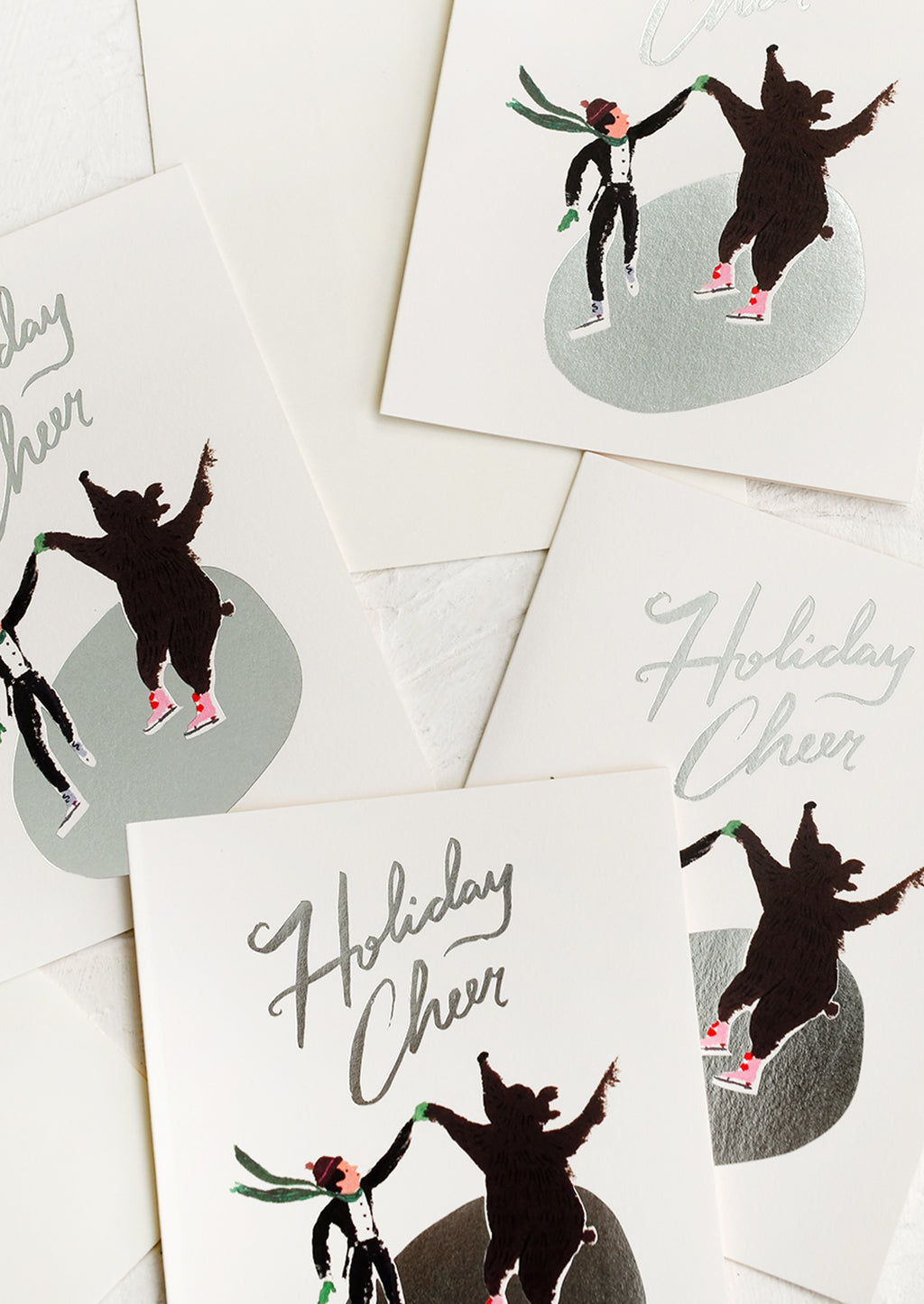 1: A set of cards depicting an ice skater and bear skating on silver pond, text reads "Holiday cheer".