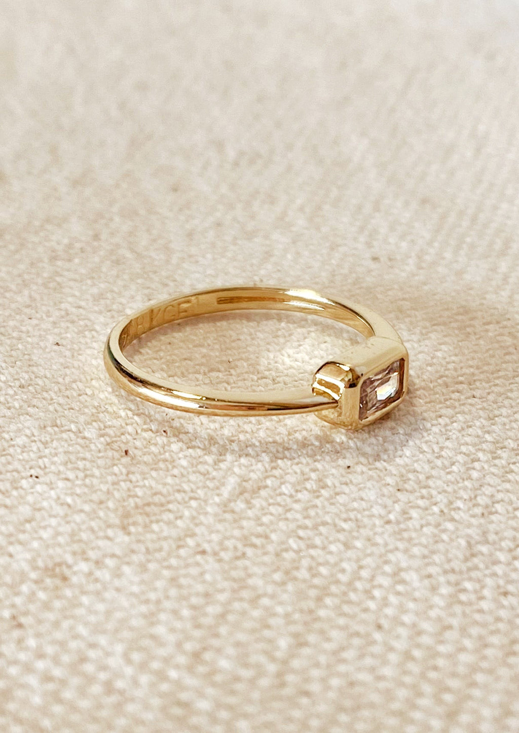 3: A gold ring with single rectangular clear stone.