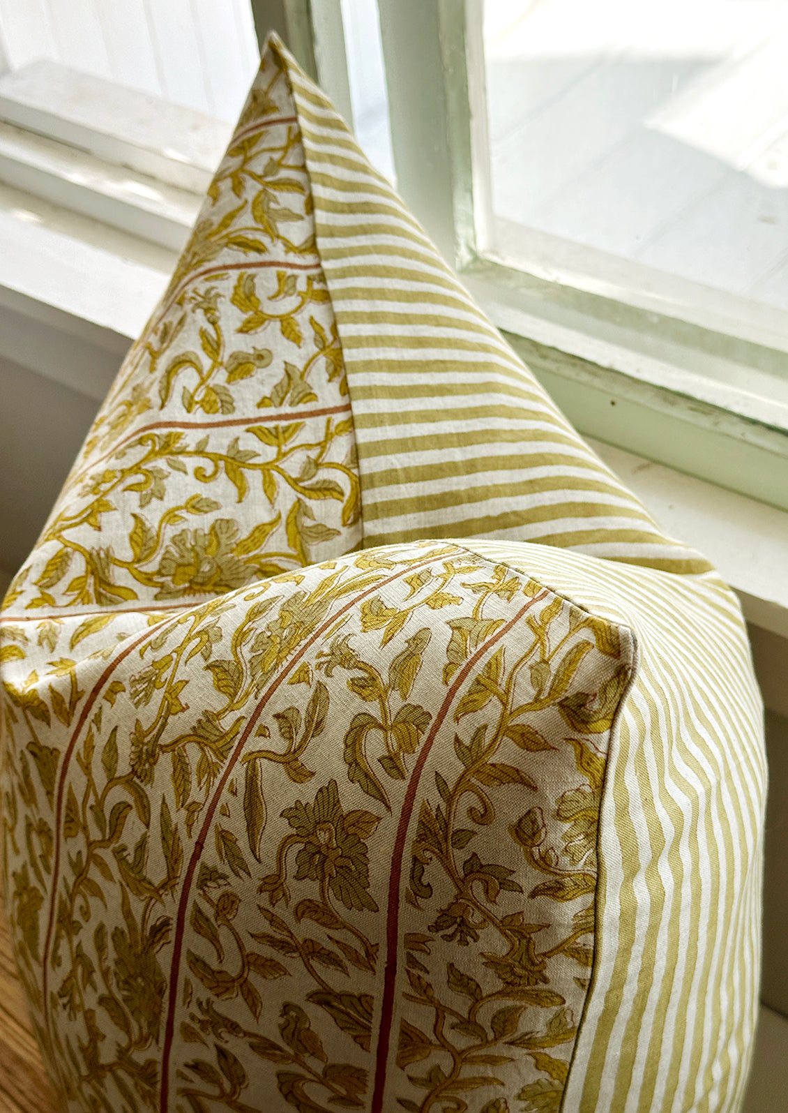 A block printed pillow with vertical stripes amidst yellow floral pattern.